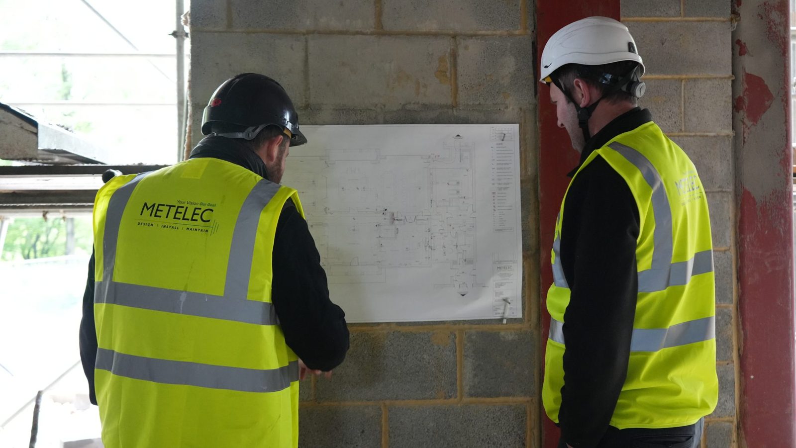 Metelec engineers reviewing electrical layout drawings on site at Woodrising
