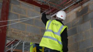 Metelec engineer fixing cables to tray during first fix at Woodrising